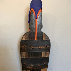May include: A wooden bottle stopper with a blue and orange wax drip design. The stopper is made from reclaimed wood and has a rustic look.