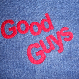 Op de afbeelding: Rode geborduurde tekst op een blauwe denim achtergrond die "Good Guys" zegt.