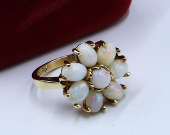 May include: A gold ring with a cluster of white opals set in a flower shape.
