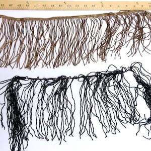 May include: Two strands of fringe trim, one brown and one black. The brown fringe is about 1 inch wide and has a gold thread running through it. The black fringe is about 1/2 inch wide. Both fringes are made of small beads.