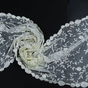 May include: A white lace shawl with a delicate floral pattern and a scalloped edge.