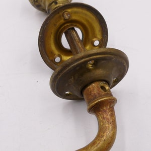 May include: An antique brass door handle set, featuring a round knob, circular backplates, and a curved lever. The hardware has a weathered appearance, suggesting a vintage or retro design, with a patina.