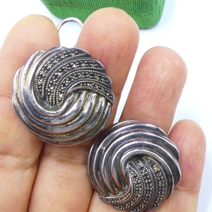 May include: A pair of silver earrings with a swirl design and black marcasite stones.