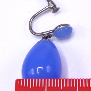 K&ouml;nnte beinhalten: Vintage Ohrring mit Schraubverschluss und einem tropfenf&ouml;rmigen, hellblauen Stein. Die Metallteile des Ohrrings sind silberfarben. Der Stein misst etwa 1 cm in der L&auml;nge. Auf wei&szlig;em Hintergrund.