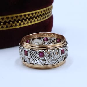 May include: A vintage ring with a delicate filigree design set in white gold and accented with red rubies and diamonds.
