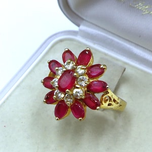 May include: A gold ring with a red ruby and clear diamond flower design.