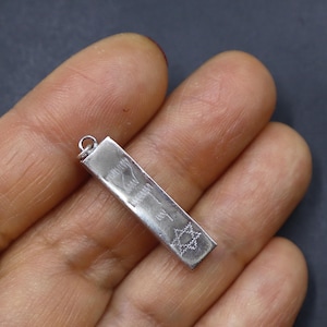 May include: Silver pendant with a rectangular shape and a star design. The pendant has an inscription that reads "Wishing you a Diamond Day".