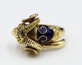 Könnte beinhalten: Ein goldener Ring mit einem blauen Emaille-Design und einem detaillierten Widderkopf. Die Widderhörner sind gekrümmt und die Emaille ist tiefblau mit goldenen Akzenten.