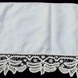 May include: White lace trim with a delicate floral pattern. The trim is made of white cotton and has a scalloped edge.