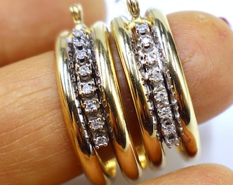 Könnte beinhalten: Goldene Creolen mit einer Reihe kleiner Diamanten, die in jeden Reifen eingefasst sind.