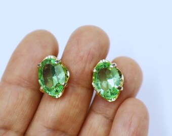 May include: A pair of gold-tone earrings with oval-shaped green gemstones.