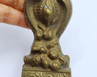 May include: A vintage brass decorative hardware piece with intricate floral designs and a textured surface. It has two holes and a detailed, ornate design.
