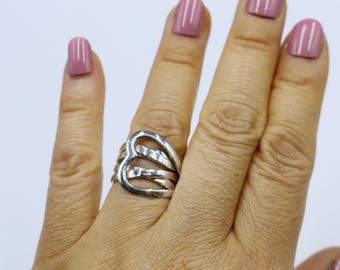 May include: A silver ring with a heart-shaped design. The ring is made of multiple bands that are intertwined.