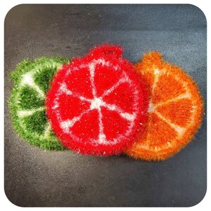 May include: Three colorful knitted dishcloths shaped like citrus fruit slices. The dishcloths are green, red, and orange.