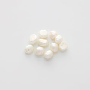 Könnte beinhalten: Eine Gruppe von zehn weißen, unregelmäßig geformten Perlen auf weißem Hintergrund.