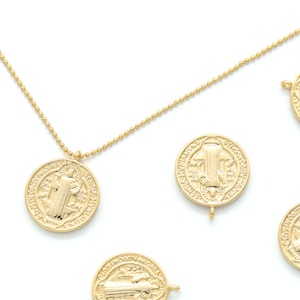 May include: A gold chain necklace with multiple gold medallions featuring a religious figure. The medallions are round and have intricate details.