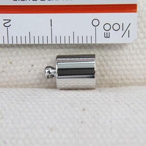 Op de afbeelding: Zilveren metalen eindkap voor koord of touw. De eindkap is ongeveer 1,2 cm lang en heeft een afgerond uiteinde.