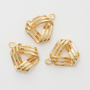 May include: Three gold-colored metal charms, each shaped as a hollow triangle formed by three layered, curved bars. Each charm features a small circular jump ring attached to one corner, designed for jewelry making and decorative attachment purposes.