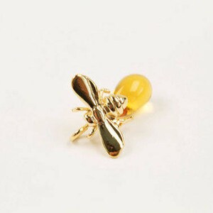 May include: A gold bee brooch with a yellow amber drop.