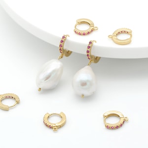 May include: Five gold hoop earrings with pink gemstones. Two of the earrings have a white pearl attached to the bottom.