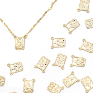 May include: A gold chain necklace with a gold pendant featuring a religious icon. The pendant is surrounded by several other gold pendants with religious icons, all scattered on a white background.