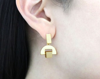 May include: Gold geometric earrings with a half-circle and square design.