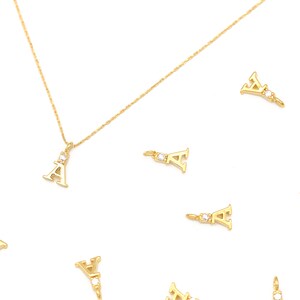 May include: A gold chain necklace with a small letter A pendant. The pendant has a small clear stone in the center. There are several other letter A pendants scattered around the necklace.