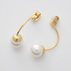 May include: A pair of gold earrings with a curved bar and a white pearl on each end.