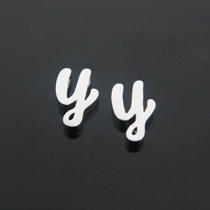 May include: Two silver-colored letter charms in the shape of the letter "y". The charms are in a cursive font.