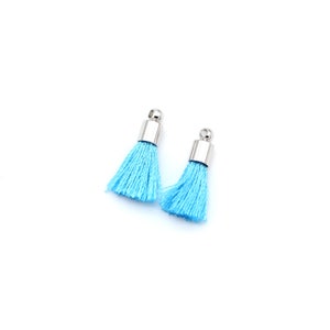 May include: Two light blue tassels with silver metal tops. The tassels are made of soft, fluffy fibres.