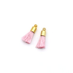 May include: Two pink tassel charms with gold metal caps. The tassels are made of soft, fluffy fibres.