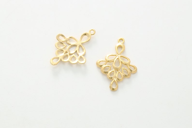 May include: Two gold-colored metal pendant charms with a delicate, intricate design resembling a cluster of small teardrop shapes. The charms have a loop at the top for attaching to jewelry.
