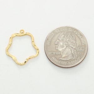 Puede incluir: Marco de metal dorado con una forma ondulada irregular. El marco es aproximadamente del tama&ntilde;o de una moneda de euro.