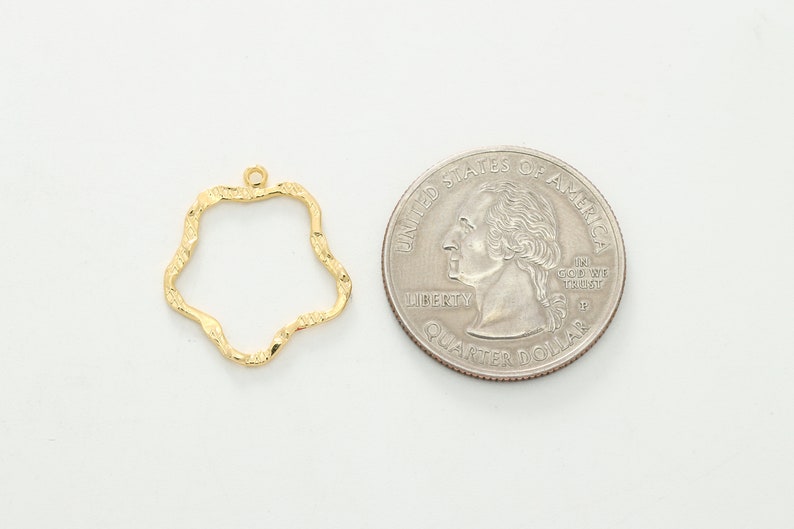 Puede incluir: Marco de metal dorado con una forma ondulada irregular. El marco es aproximadamente del tama&ntilde;o de una moneda de euro.