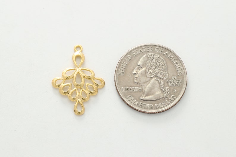 May include: Gold-toned metal pendant with a delicate, intricate design resembling a cluster of leaves or flowers. The pendant is about the size of a US quarter.