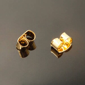 Peut inclure: Deux dos d'oreille en or. Chaque dos a deux boucles, l'une au-dessus de l'autre.