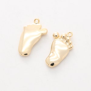 May include: Two gold-tone baby foot charms. One charm has a simple foot design, while the other has a foot with five small circles around the ankle.