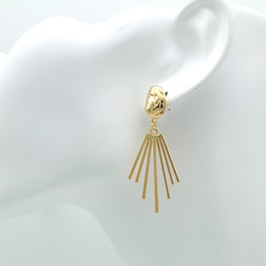 May include: Gold dangle earrings with a textured, round top and a fan-shaped design with multiple thin, gold bars.