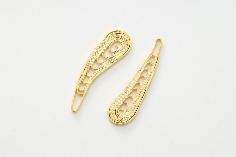 May include: Two gold filigree earrings in the shape of a teardrop with a swirl at the top.