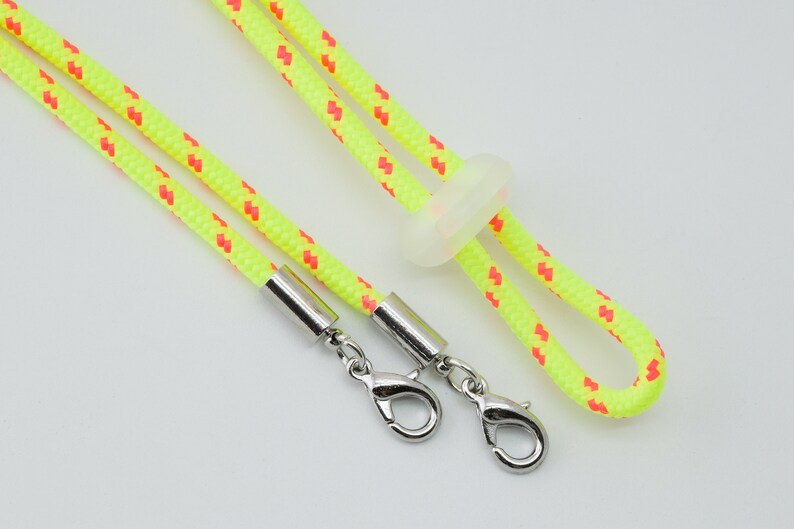 May include: A yellow and red lanyard with silver clasps and a clear plastic slider.