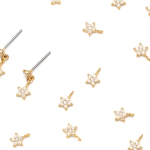 May include: A pair of gold star-shaped earrings with dangling star charms. Each star is adorned with clear sparkling crystals.