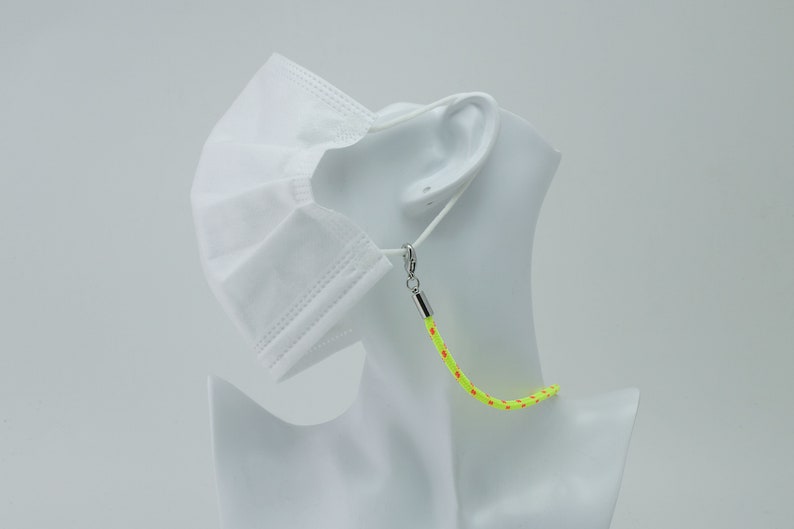 May include: A yellow and orange face mask lanyard with silver clasps. The lanyard is worn around the neck of a white mannequin.