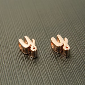 May include: Two rose gold metal letter charms in the shape of the letter "Y".