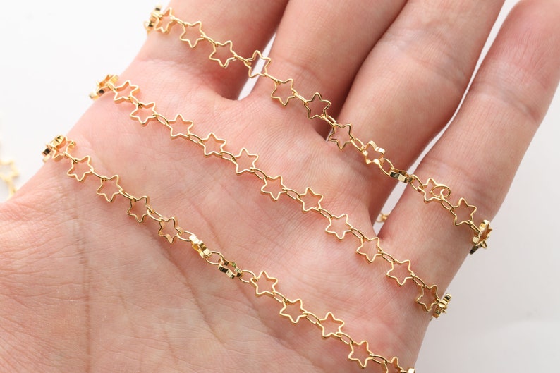 Op de afbeelding: Gouden sterketting, een delicate ketting met kleine stervormige schakels. De ketting wordt getoond in een hand, met meerdere strengen van de ketting.