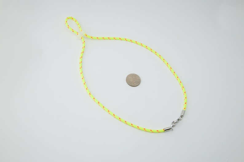 May include: A bright yellow lanyard with red accents and a silver clasp. The lanyard is approximately the size of a US quarter.
