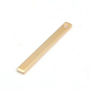 May include: A gold-colored metal bar with a small hole at the top. The bar is about 1.5 inches long and 0.25 inches wide.