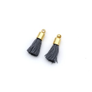 May include: Two gray tassel charms with gold metal tops.
