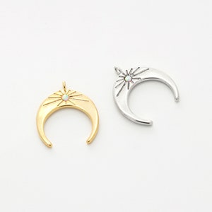 May include: Two crescent moon charms with a starburst design and an iridescent opal stone in the centre. One charm is gold and the other is silver.
