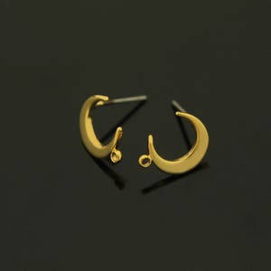 Könnte beinhalten: Ein Paar goldene Halbmond-Ohrring-Findings mit einem Sprungring, der an der Unterseite jedes Mondes befestigt ist.
