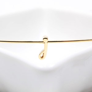 May include: A gold-colored bracelet with a small, dangling letter 'J' charm.